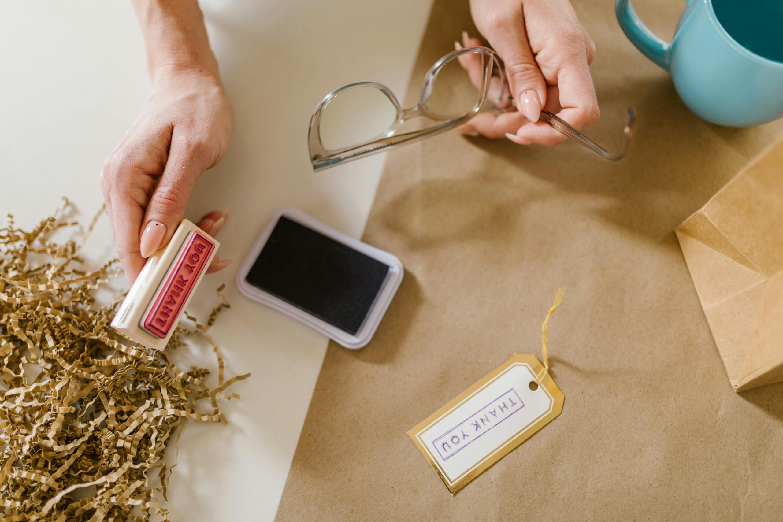 Flat lay image of hands using a thank you stamp. Perfect for craft and creative workspace themes.